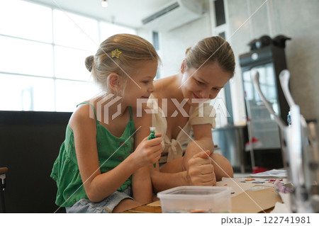 Mother and her daughter paint Halloween cookies  122741981