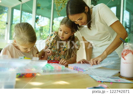 Teacher in workshop teched two girls how to assemble a thermo mosaic Teacher in workshop teched two girls how to assemble a thermo mosaic 122742071