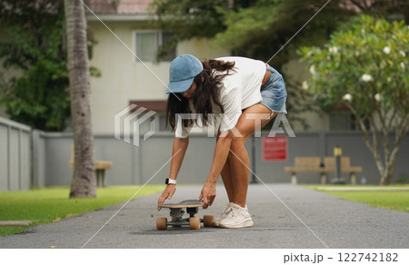 A young woman is skillfully riding a skateboard down a scenic park A young woman is skillfully riding a skateboard down a scenic park 122742182