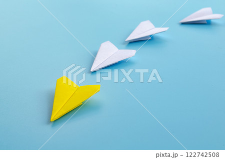 Origami paper airplane with yellow airplane leading the rest of white airplane 122742508