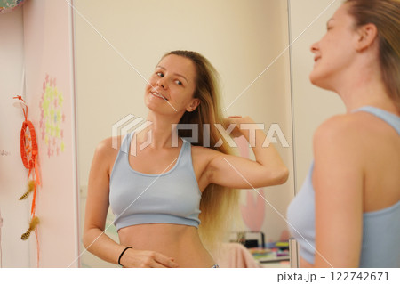 Young woman in a modern bathroom washing her face and brushing her teeth  122742671