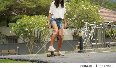 A young woman is skillfully riding a skateboard down a scenic park A young woman is skillfully riding a skateboard down a scenic park 122742681