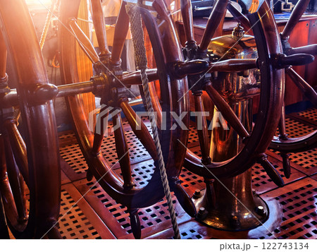 A row of wooden steering wheels located on an old vessel A row of wooden steering wheels located on an old vessel 122743134
