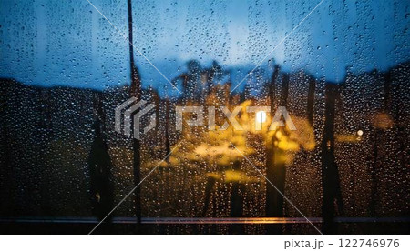 夕方に降る雨のガラス窓についた水滴・雨粒の背景素材 122746976