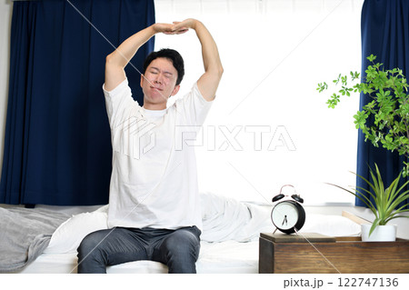 起床後にベッドの上でストレッチをする男性 122747136