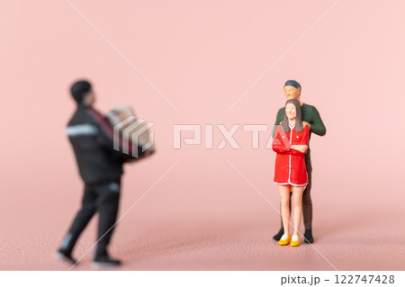 Miniature figurine scene depicting a man carrying presents towards a couple, with the woman appearing surprised Miniature figurine scene depicting a man carrying presents towards a couple, with the woman appearing surprised 122747428