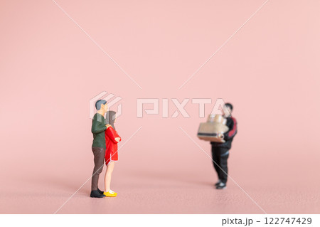 Miniature figurine scene depicting a man carrying presents towards a couple, with the woman appearing surprised Miniature figurine scene depicting a man carrying presents towards a couple, with the woman appearing surprised 122747429