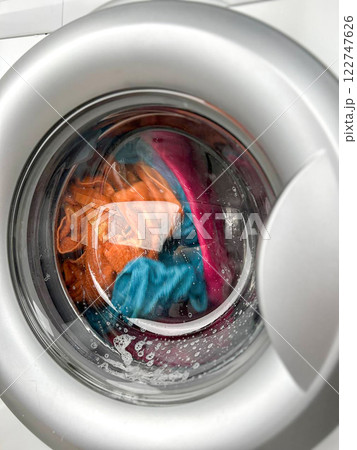 A woman's hand throws a laundry capsule into the washing machine 122747626