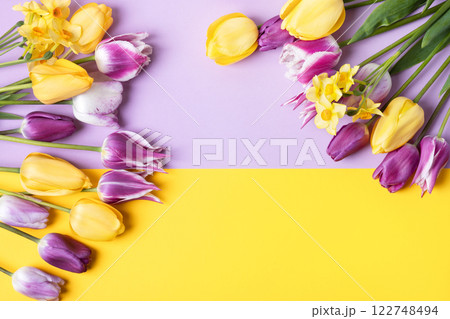 Spring flower of purple and yellow tulips and yellow daffodils on purple yellow background with a place for text. Copy space, flat lay, mockup for special offers as advertising or other ideas 122748494