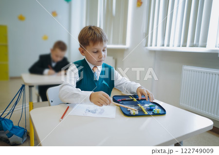 cute little boy sittimg at the class in school. cute little boy sittimg at the class in school. 122749009
