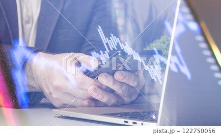 Mobile financial analysis: hands using smartphone and laptop with digital visualization of stock market data 122750056