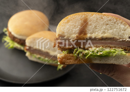 ハムカツバーガーを手で持ち上げる 122751672