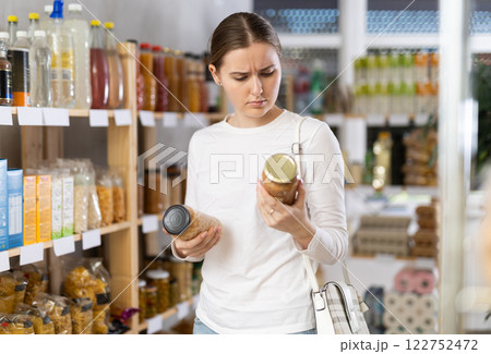 Woman carefully chooses canned beans and lentils 122752472