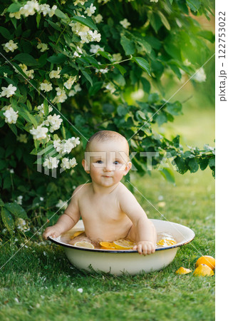 Baby Sitting In Bowl With Citrus And Water Outdoors Baby Sitting In Bowl With Citrus And Water Outdoors 122753022
