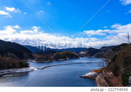 雪景色の奈良布目ダム　青空を映す駐車場付近から見えるダム湖の水面① 122754658