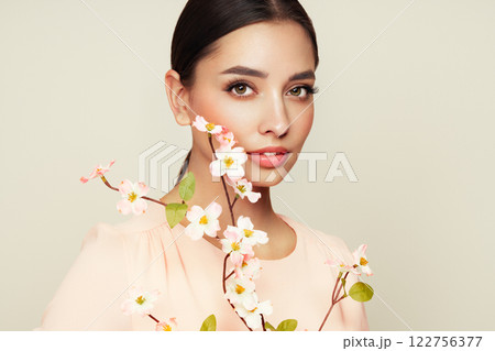 Beautiful young woman with a cherry blossom branch Beautiful young woman with a cherry blossom branch 122756377