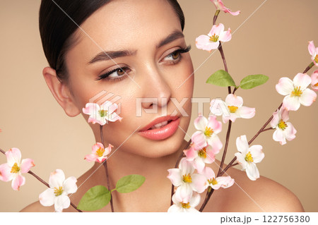 Beautiful young woman with a cherry blossom branch Beautiful young woman with a cherry blossom branch 122756380