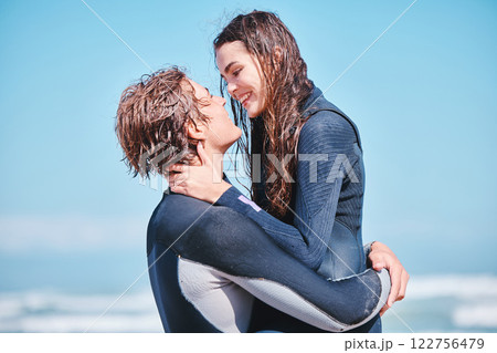 Love, surf and summer with a couple hugging on the beach with the sea or ocean in the background after surfing. Romantic young man and woman embracing face to face under a blue sky during the day Love, surf and summer with a couple hugging on the beach with the sea or ocean in the background after surfing. Romantic young man and woman embracing face to face under a blue sky during the day 122756479