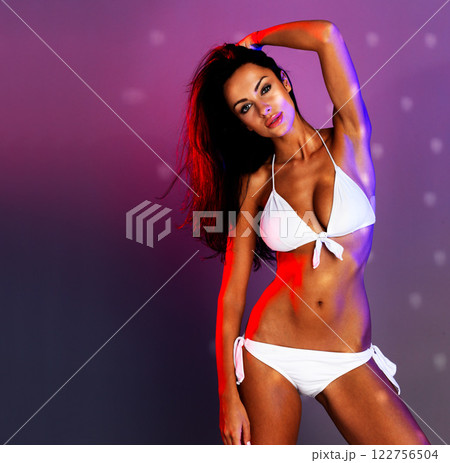 Sexy, fitness and body beauty model in a bikini showing skin and stomach with mockup space. Portrait of a healthy, young and sensual woman with confidence, mock up purple background and disco light 122756504