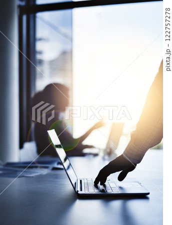 Silhouette of the hand of a businessman working on a laptop in an office with sunlight and a blurred shadow of a woman in the background with bokeh. Outline of a male brainstorming in the office. 122757278
