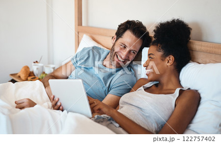 Laughing married couple with a tablet in bed watching funny comedy film or movie together on the weekend indoors at home. Loving, smiling and romantic husband and wife looking at meme on social media Laughing married couple with a tablet in bed watching funny comedy film or movie together on the weekend indoors at home. Loving, smiling and romantic husband and wife looking at meme on social media 122757402