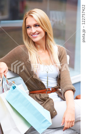 Shopping, fashion and retail, a woman with a smile, resting outside a mall. Relax on a bench, a happy customer after discount sale at the shopping mall. City lady with designer boutique shopping bags 122757422