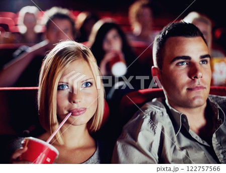 Couple in dark movie theatre, drinking cola on date in cinema and man and woman watching a film together for entertainment. Face of happy, dating and fun boyfriend and girlfriend at the movies 122757566