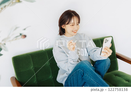 ソファでスマホを使う女性　 122758138
