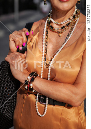 Close-up woman wearing pearl necklace, various jewelry and Accessories, beautiful golden silk dress 122758273