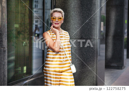 Portrait Beautiful Mature Woman with Short Hair, pearl necklace and yellow Sunglasses in stylish clothes Striped sleeveless top at Summer Day Outdoors in City, Confidence, fashion and Style Portrait Beautiful Mature Woman with Short Hair, pearl necklace and yellow Sunglasses in stylish clothes Striped sleeveless top at Summer Day Outdoors in City, Confidence, fashion and Style 122758275
