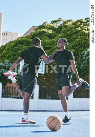 Fit, active and sporty young basketball players stretch or warm up their legs on a basketball court. Determined male athletes prepare muscle fitness before practicing or training at a sports venue 122758284