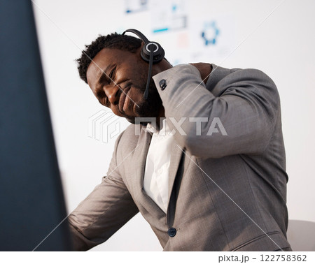 Stressed, pain and tired call center agent with a shoulder injury feeling unhappy and overworked in the office. Young male customer service consultant with suffering from a painful neck 122758362