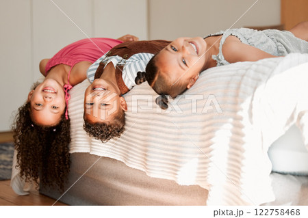 Fun, playful and silly kids lying on a bed with cute hairstyle and smiling portrait. Little siblings relaxing, playing indoors showing growth, child development and childhood innocence 122758468