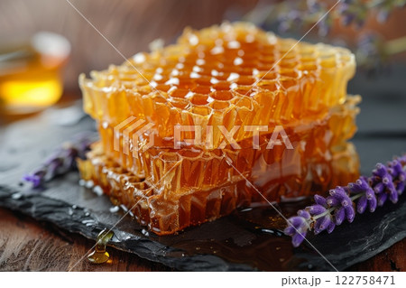 A golden honeycomb delight piece, with honey dripping from its edges, placed elegantly on a dark slate plate. 122758471