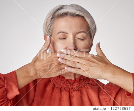 Senior, hands and mouth of an elderly woman covering her teeth or lips with hand against a grey studio background. Mature and aging woman keeping secrets, not talking and hiding the truth or gossip. Senior, hands and mouth of an elderly woman covering her teeth or lips with hand against a grey studio background. Mature and aging woman keeping secrets, not talking and hiding the truth or gossip. 122758657
