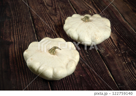 Two white pattypan squash on dark wooden board 122759140