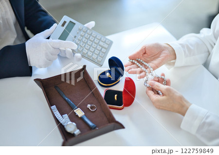 貴金属を査定する買取専門業者とミドル女性の手元 122759849