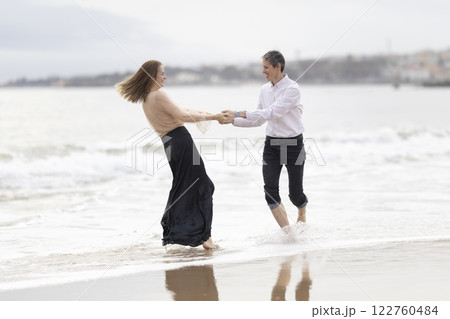 Happy couple holding hands and spinning on the beach Happy couple holding hands and spinning on the beach 122760484