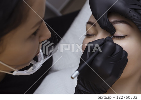 Permanent makeup. Cosmetologist tattoo artist applies a contour to the client's eyelid for subsequent application of eye tattooing 122760532