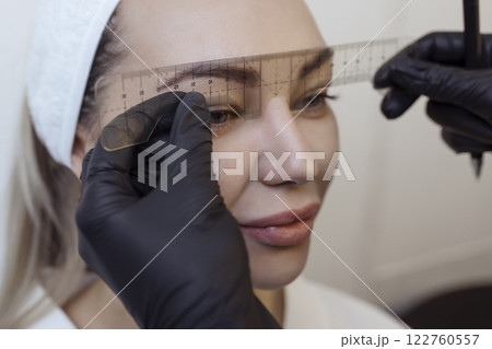 Eyebrow tattooing .Permanent eyebrow makeup master applies the contour with ruler on the client's eyebrow 122760557