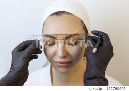 Eyebrow tattooing .Permanent eyebrow makeup master applies the contour with thread on the client's eyebrow 122760605