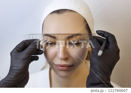 Eyebrow tattooing .Permanent eyebrow makeup master applies the contour with ruler on the client's eyebrow 122760607
