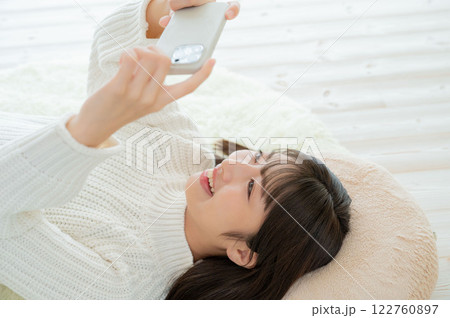 仰向けでスマホを操作する日本人女性 仰向けでスマホを操作する日本人女性 122760897