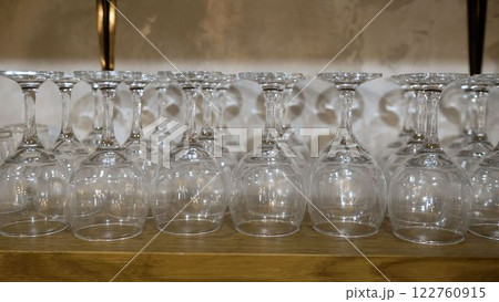 Empty wine glasses drying upside down on wooden shelf 122760915