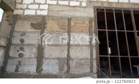 Construction workers reinforcing wall with metal mesh and cement Construction workers reinforcing wall with metal mesh and cement 122760923