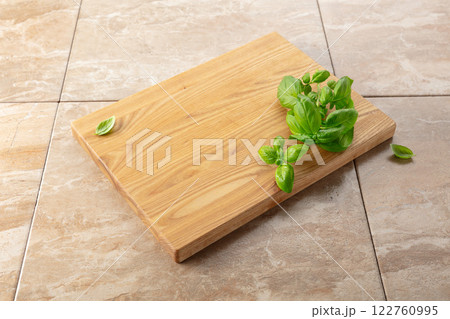Cutting board and basil on a kitchen table. Cutting board and basil on a kitchen table. 122760995