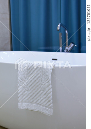 Towel is hanging on edge of tub. Foot towel. Bathroom accessories. Concept of hygiene and comfort. Bathroom interior. 122761031