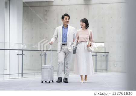 キャリーバッグを持って歩く笑顔の50代の夫婦  キャリーバッグを持って歩く笑顔の50代の夫婦  122761630
