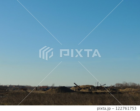 mining and crushing of natural stone on open flat terrain, piles of crushed rock at the site of soil extraction, machinery and piles of gravel and screenings view from afar mining and crushing of natural stone on open flat terrain, piles of crushed rock at the site of soil extraction, machinery and piles of gravel and screenings view from afar 122761753