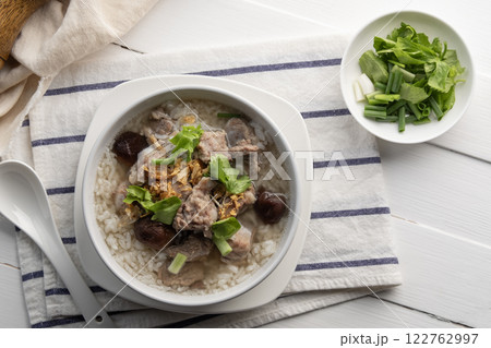 Pork Porridge.Boiled rice with Pork Baby Back Ribs or pork cartilage with shitake mushroom in white bowl.Asian breakfast style.Top view. Pork Porridge.Boiled rice with Pork Baby Back Ribs or pork cartilage with shitake mushroom in white bowl.Asian breakfast style.Top view. 122762997